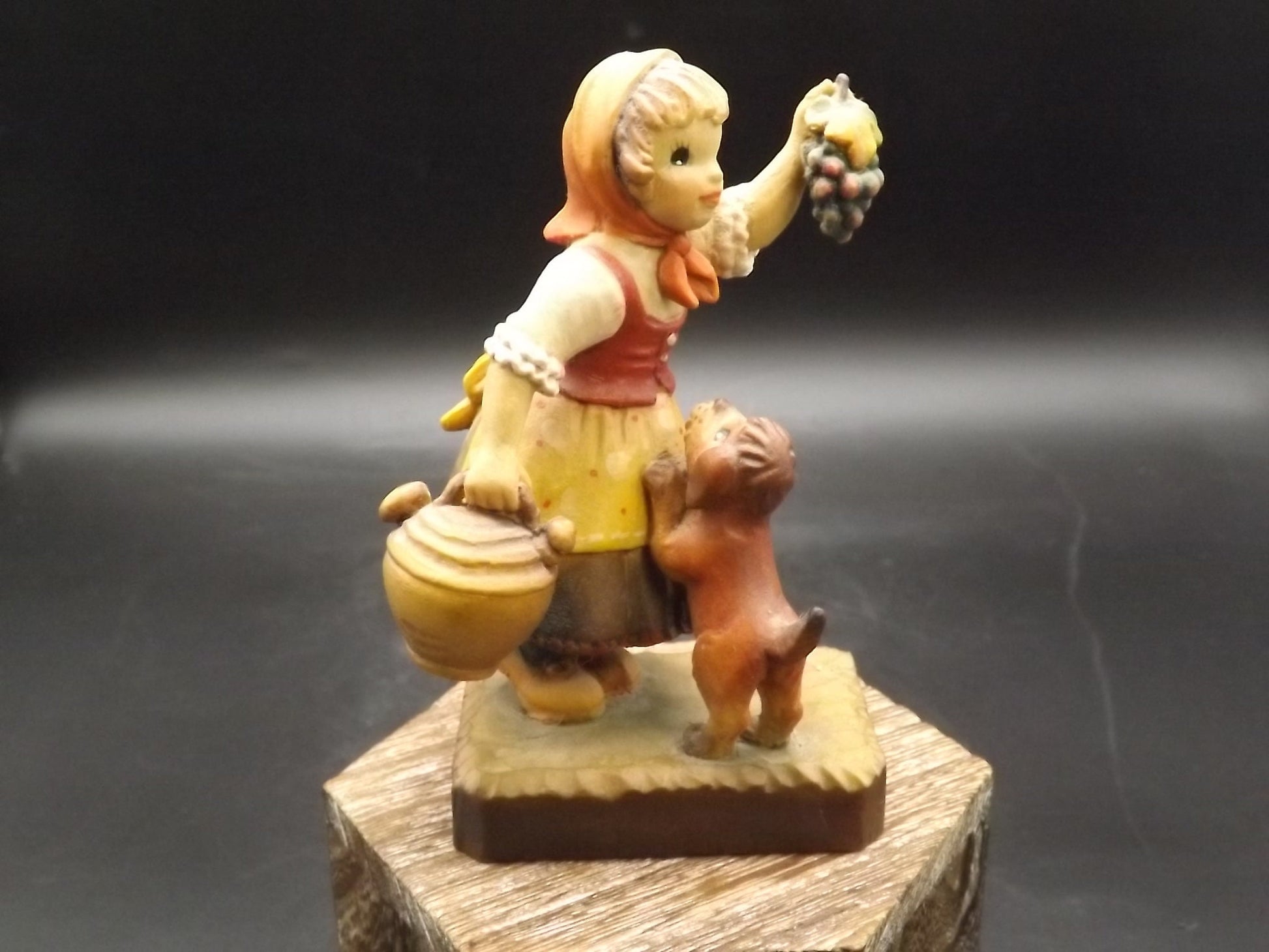 Vintage Anri "Harvest Help" carved wood figurine. Designed by Juan Ferrandiz. Young girl holding a bunch of grapes with her puppy.