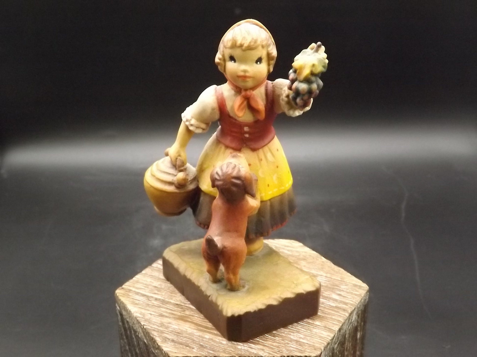 Vintage Anri "Harvest Help" carved wood figurine. Designed by Juan Ferrandiz. Young girl holding a bunch of grapes with her puppy.