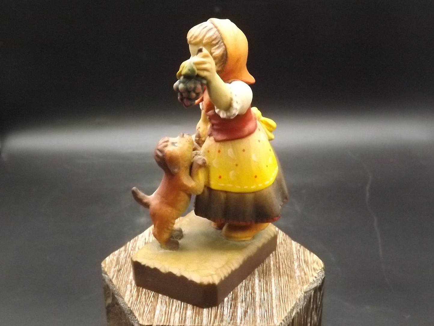 Vintage Anri "Harvest Help" carved wood figurine. Designed by Juan Ferrandiz. Young girl holding a bunch of grapes with her puppy.
