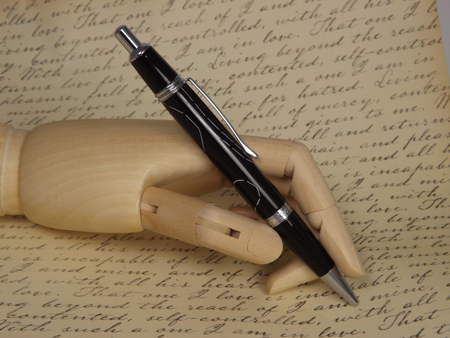 Handmade Chrome Sierra Button Click Pen with a black acrylic body showing white accents.